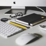 Desk with glasses, highlighter, pen, notebook, mouse, keyboard, computer, nicholas fainlight stay active while working desk job